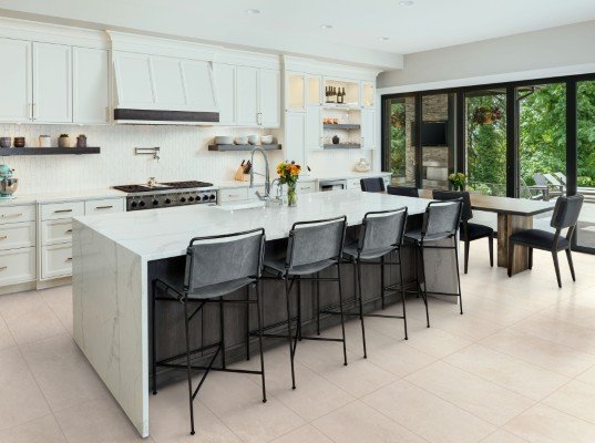 beautiful kitchen in new luxury home with island, pendant lights, oven, range, and hardwood floors.
